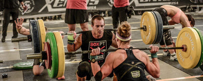 Dos atletas en una competición de Crossfit haciendo una sentadilla